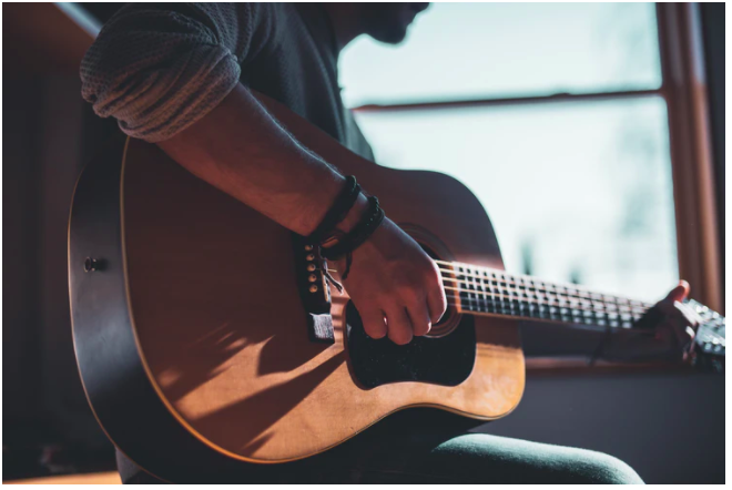 Gitarre spielender Mann, von der Sonne beleuchtet