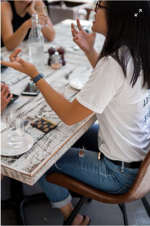 woman sitting on a chair chatting with other people