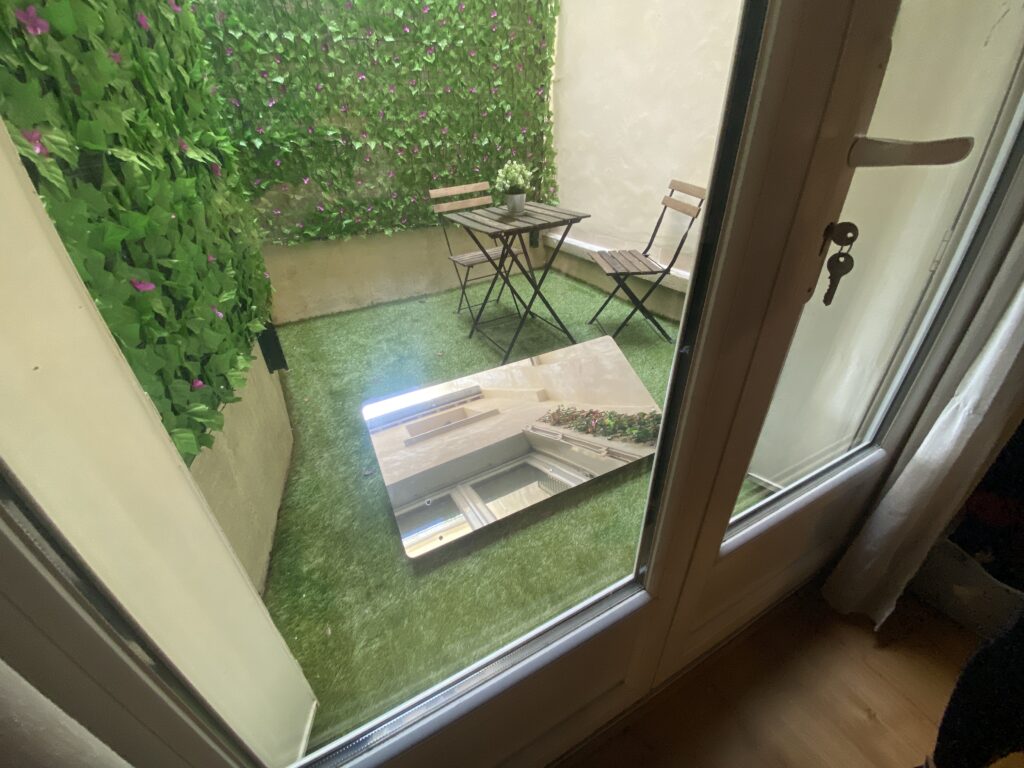 Placé devant la porte-fenêtre du studio, le Réflecteur de terrasse projette la lumière du ciel pour illuminer un studio sombre