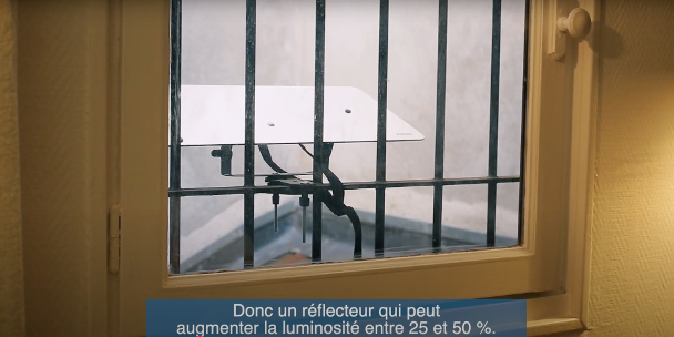 Un Réflecteur Balcon Espaciel est fixé sur les barreaux de la fenêtre pour éclairer le studio en rez-de-chaussée